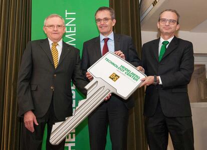 Three men in business suits are holding an oversize key