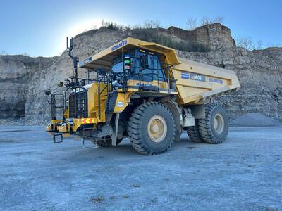 Yellow haul truck in a quarry, with a rock face in the background