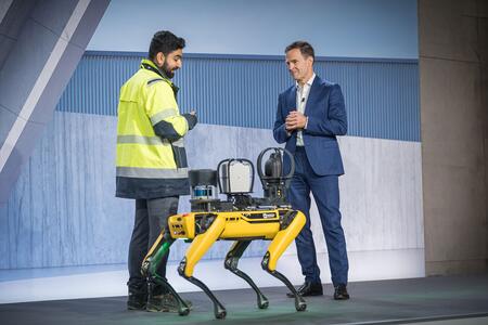 Zwei Männer stehen in einer modernen Umgebung neben einem gelben Roboterhund.