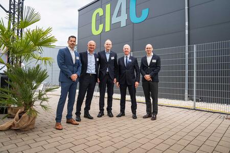Five men in business attire stand in front of a building with CI4C branding, suggesting a professional or corporate event.
