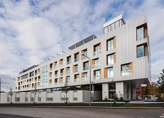 Modern building with white and wood facade under a partly cloudy sky
