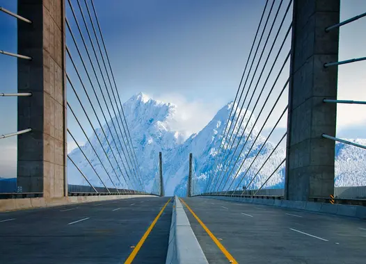 A modern suspension bridge with a central roadway flanked by tall, narrow towers supporting numerous cables. 