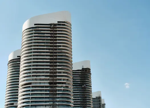 Modern high-rise buildings with curved architecture under a clear blue sky.